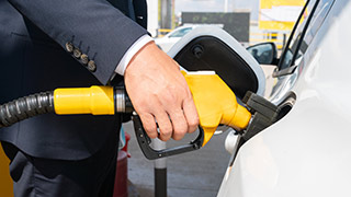 Grande plano de mão de homem a atestar o carro num posto de combustível